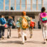 Little Kids Schoolchildren Pupils Students Running Hurrying To The School Building For Classes Lessons From To The School Bus. Welcome Back To School. The New Academic Semester Year Start